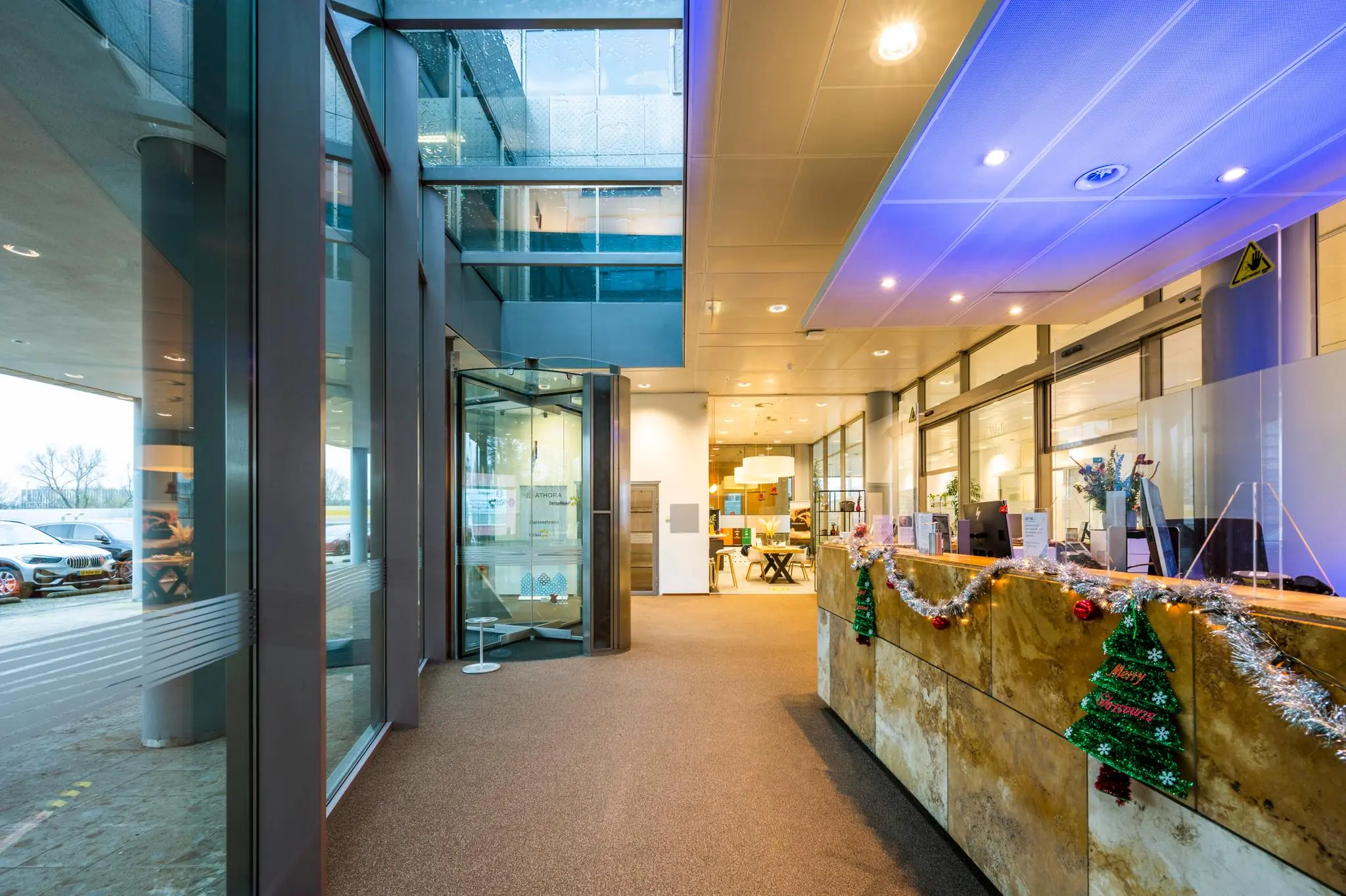 Ingang en receptiebalie van een modern kantoorgebouw aan de Burgemeester Rijnderslaan, feestelijk versierd voor Kerst.